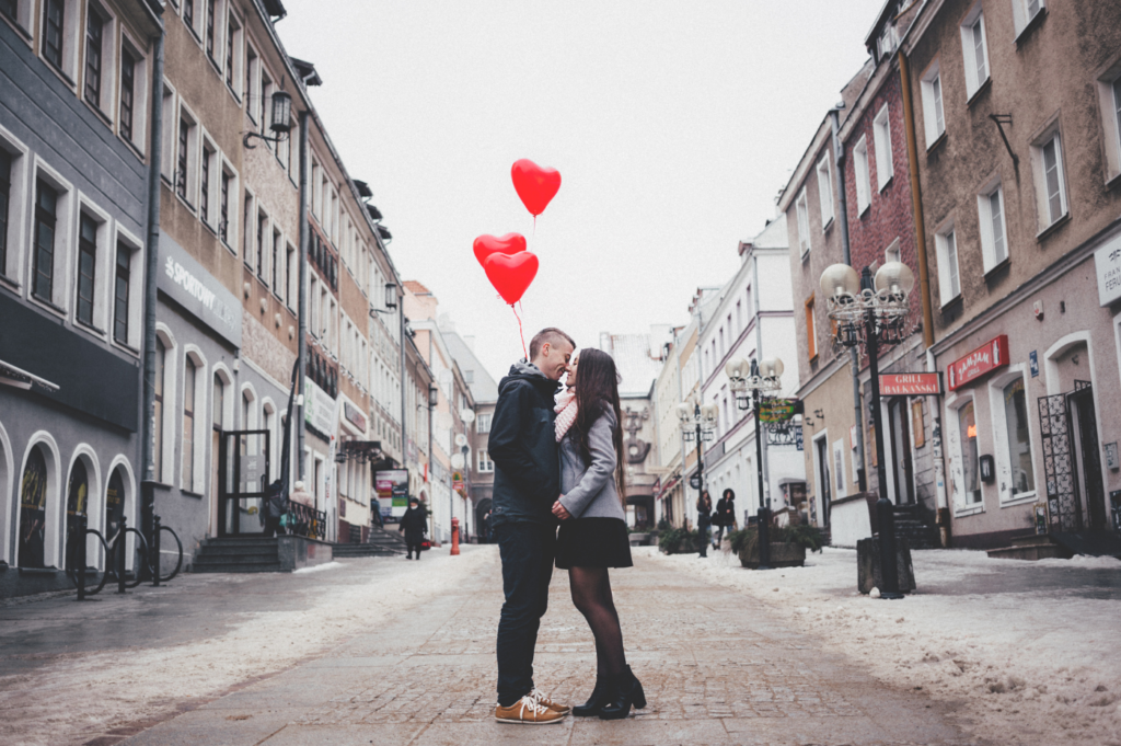 A young man and woman kissing with red heart shaped balloons. Demi-sexuals feel sexual desires after an emotional connection has been established.